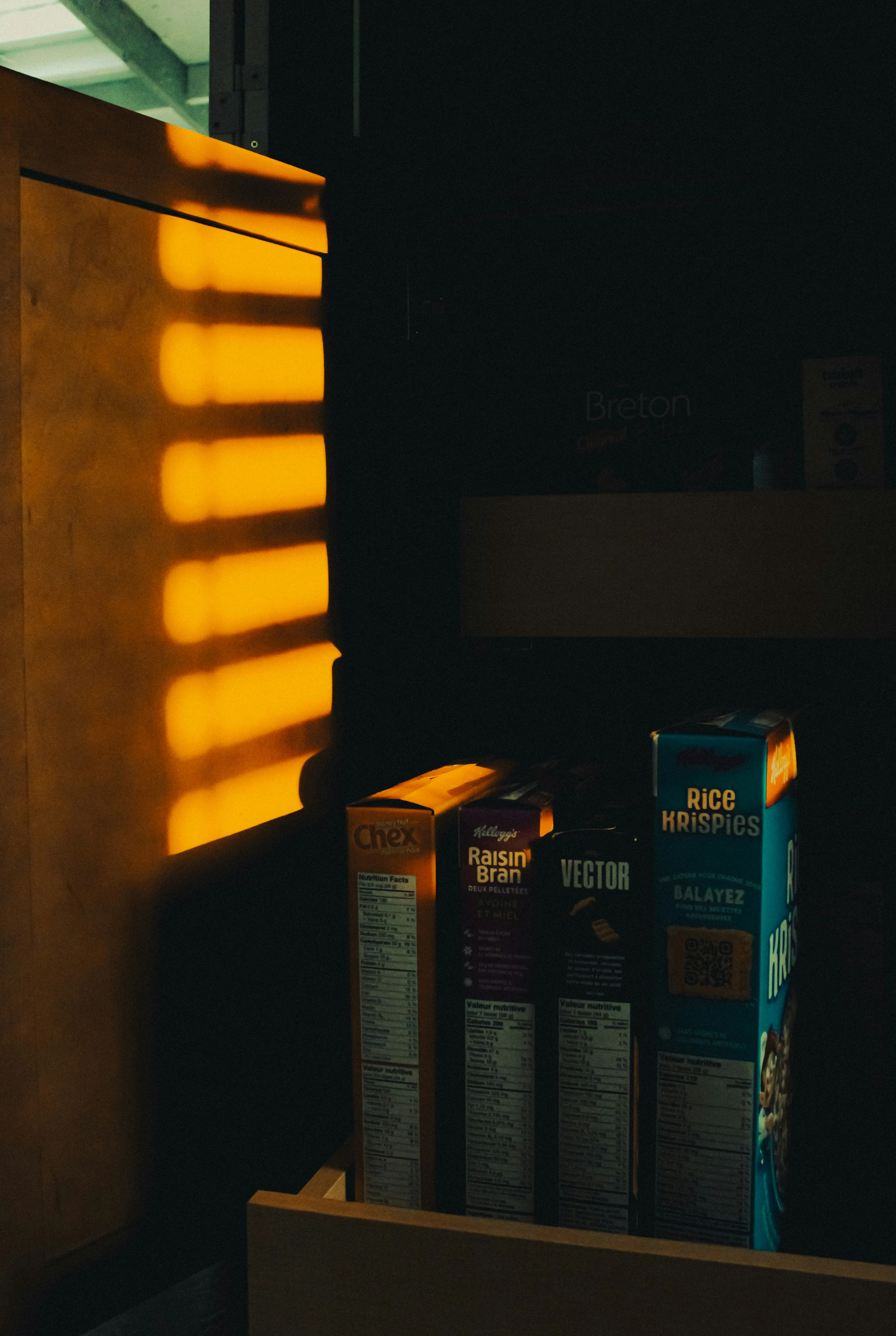 Cereal boxes lined up on a warehouse shelf in dramatic warm light