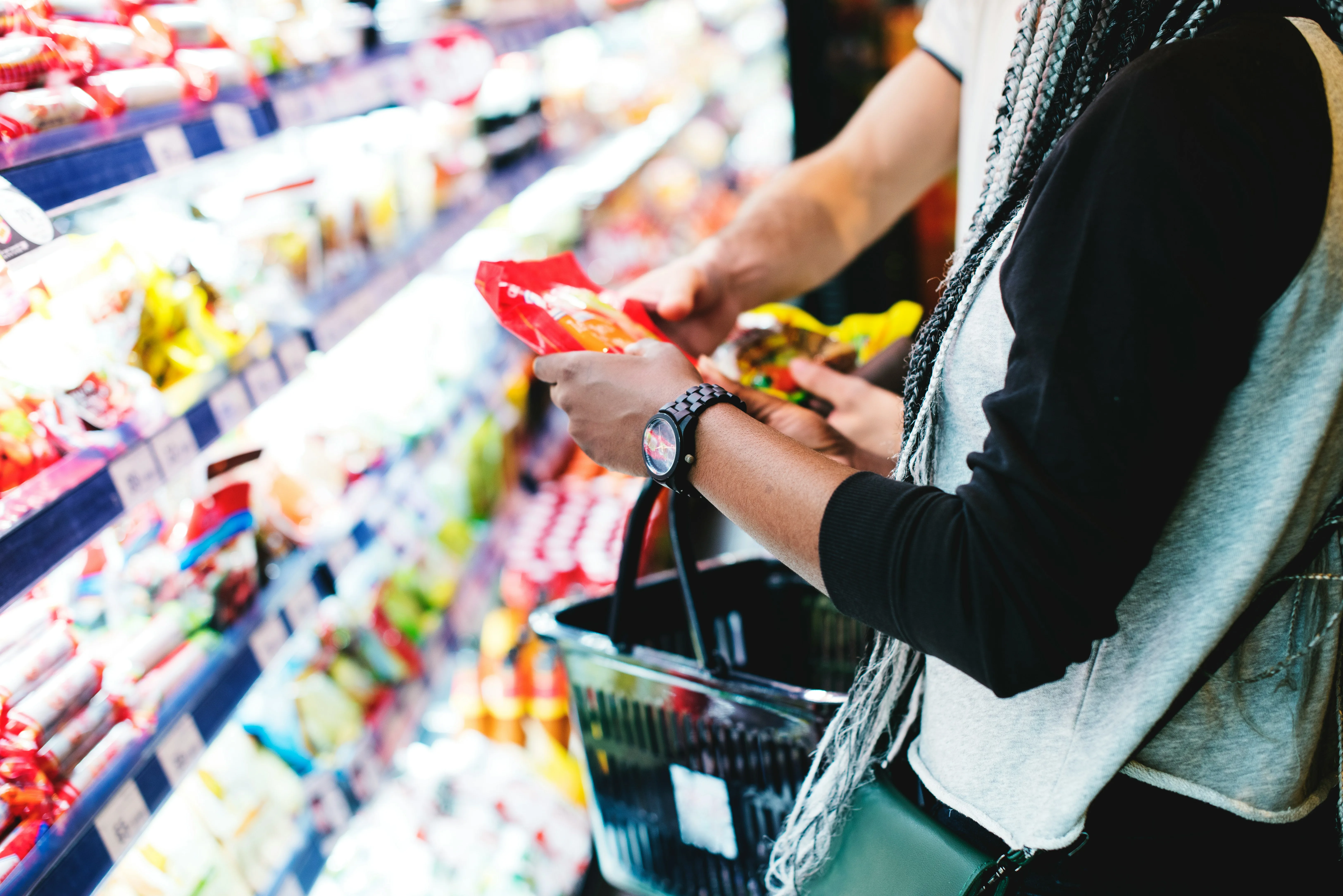 A shopper examines a packaged snack on a brightly lit grocery shelf