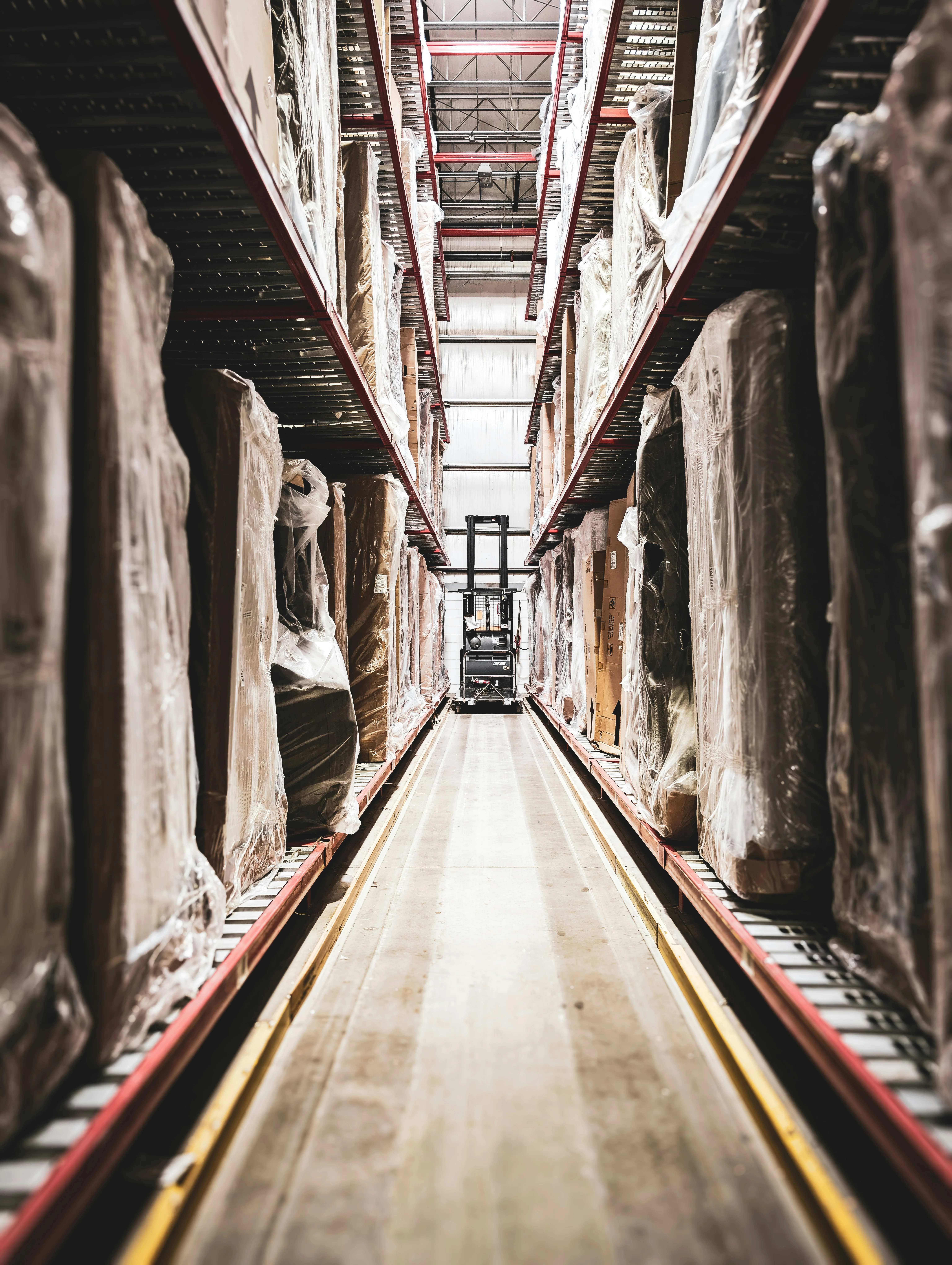 Reach truck navigating warehouse aisle between towering pallet racks