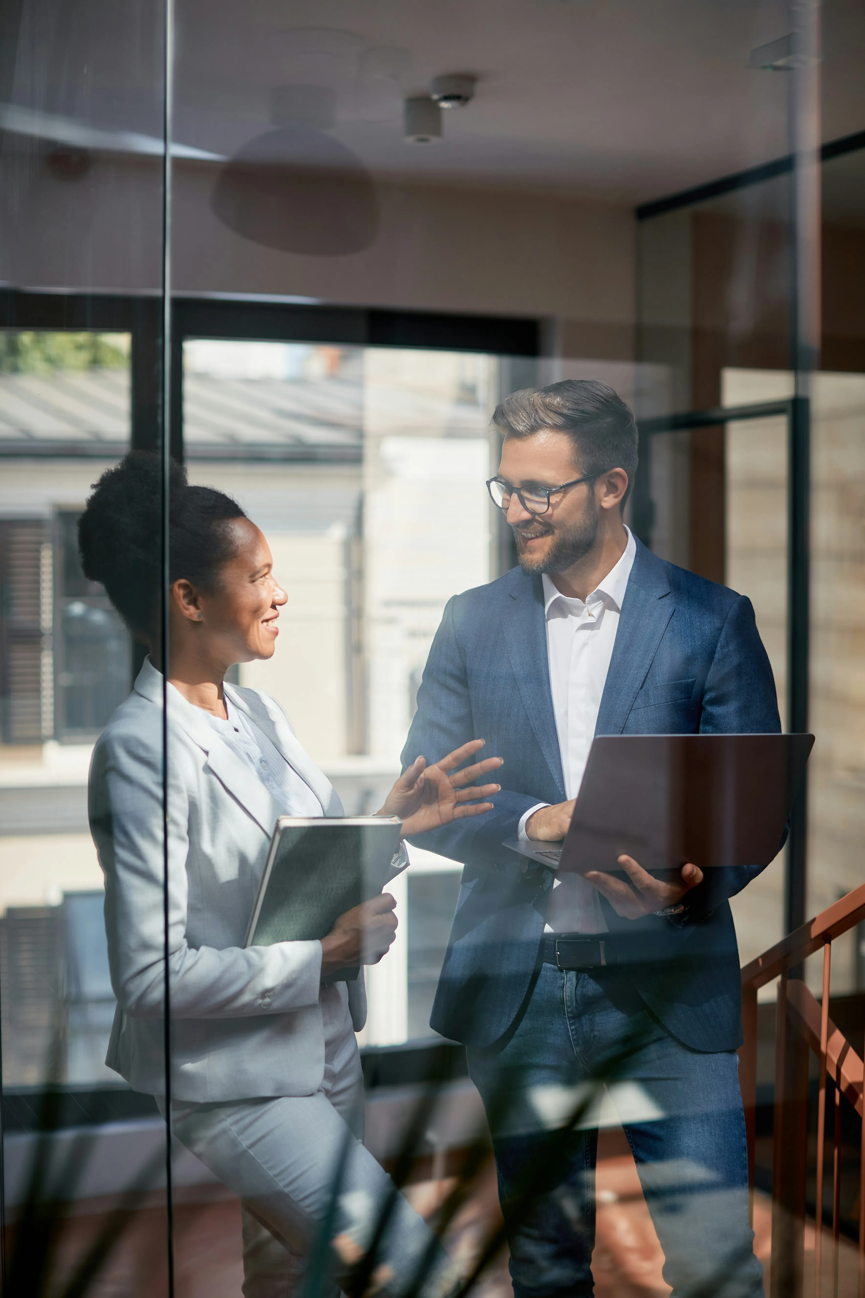Two business professionals discussing operations in modern glass office