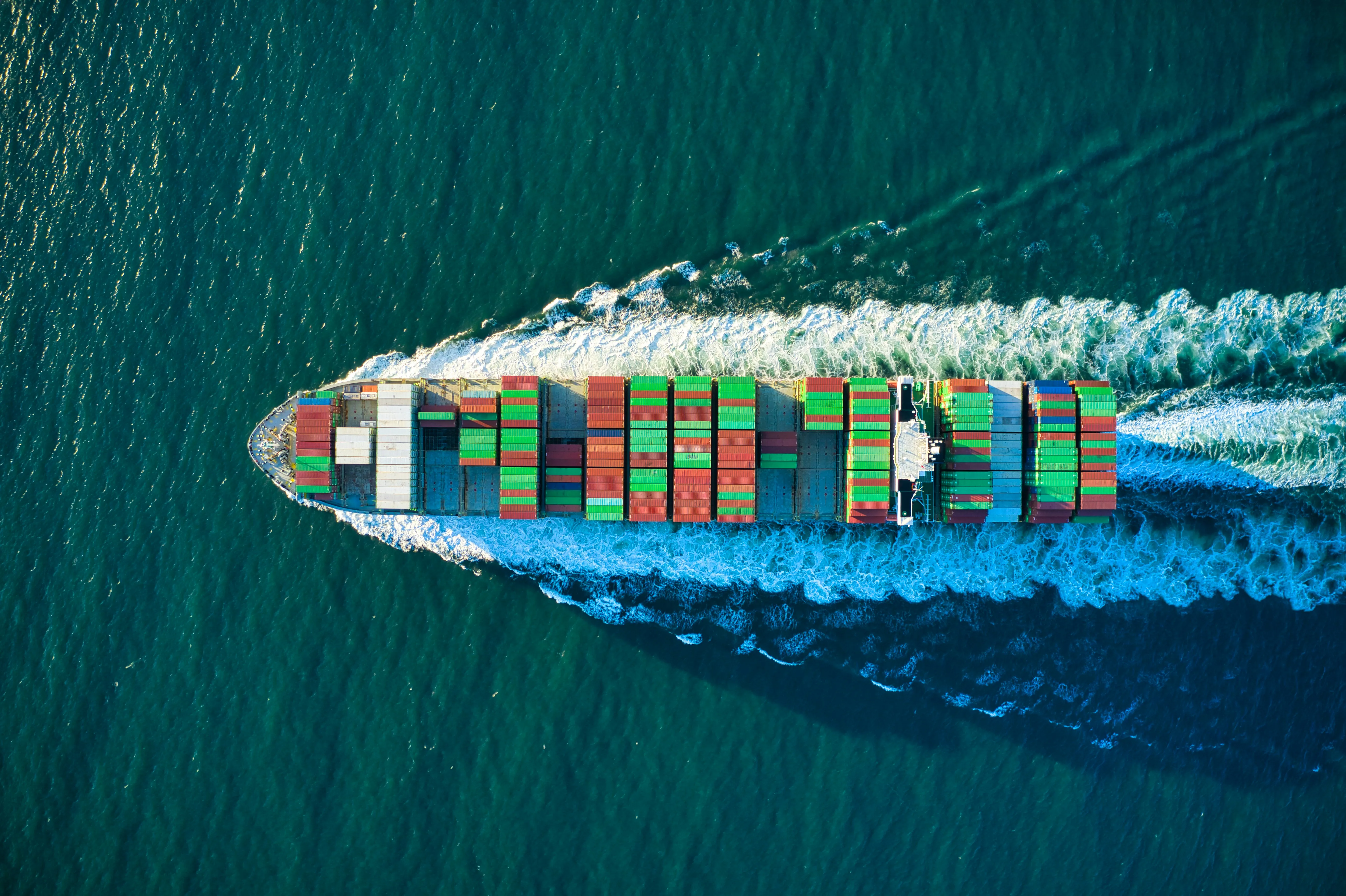 Aerial view of container ship cutting through turquoise ocean