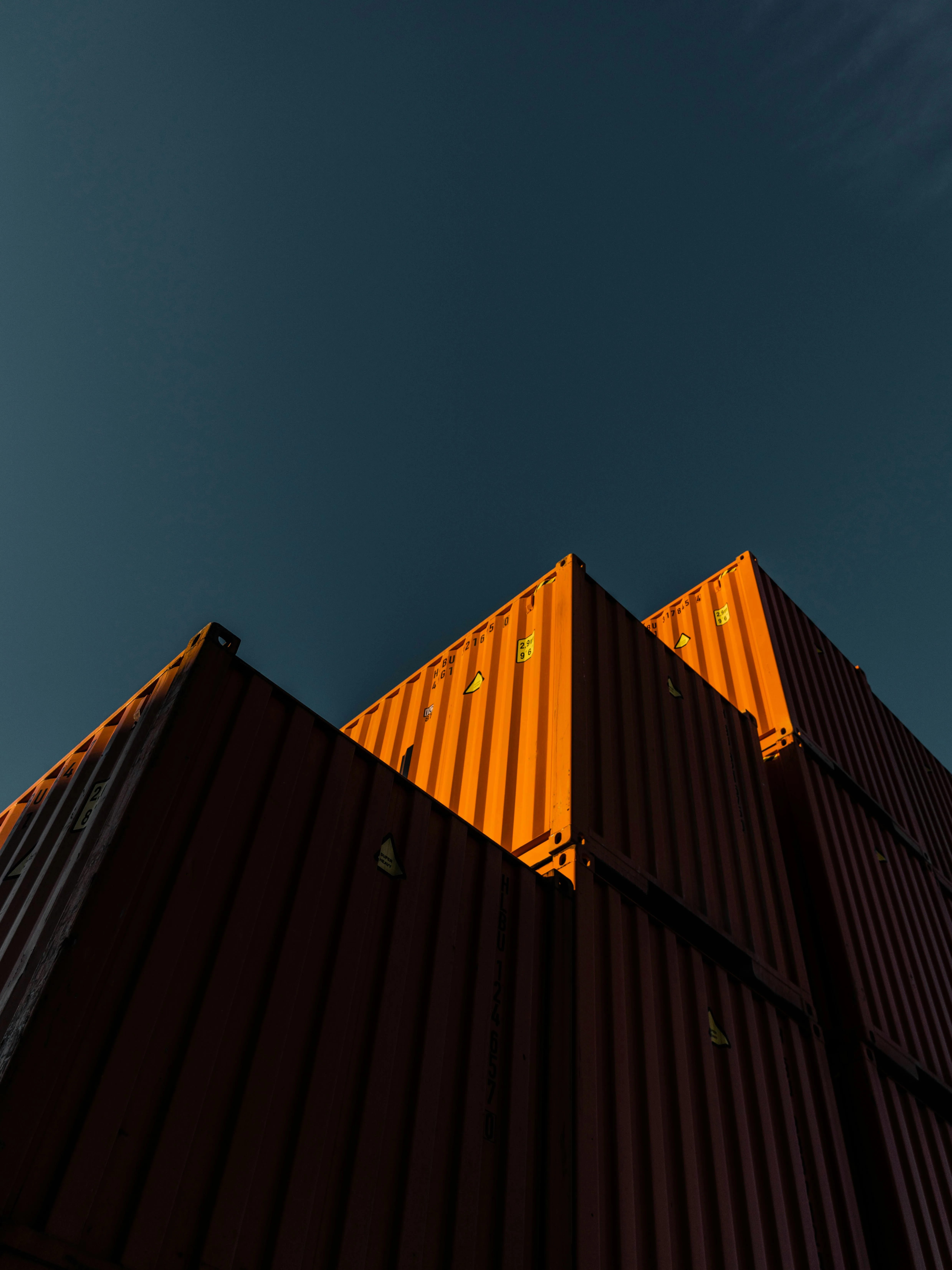 Shipping containers stacked against dramatic sunset sky