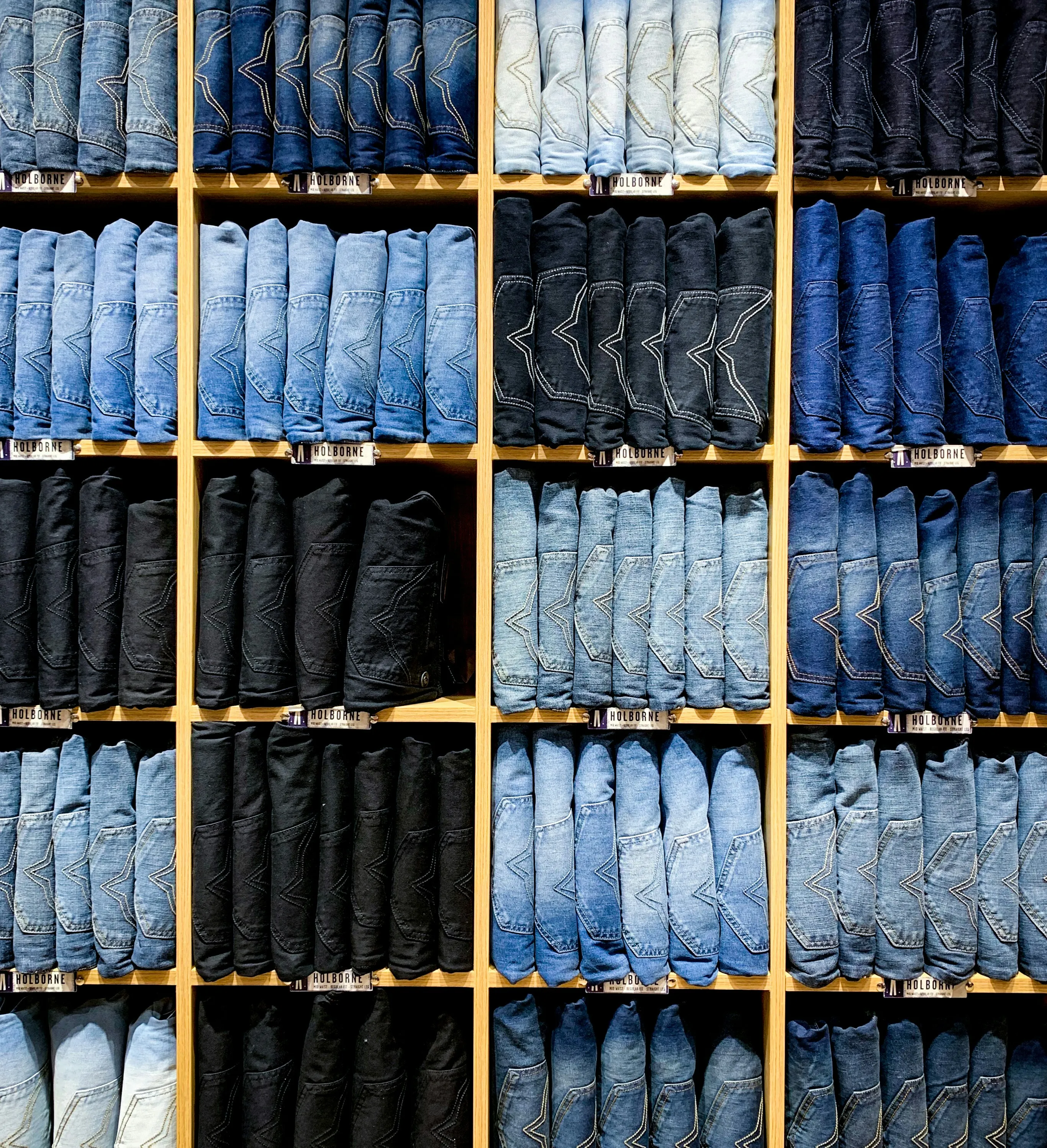 Neatly folded denim jeans organized in wooden cubbies
