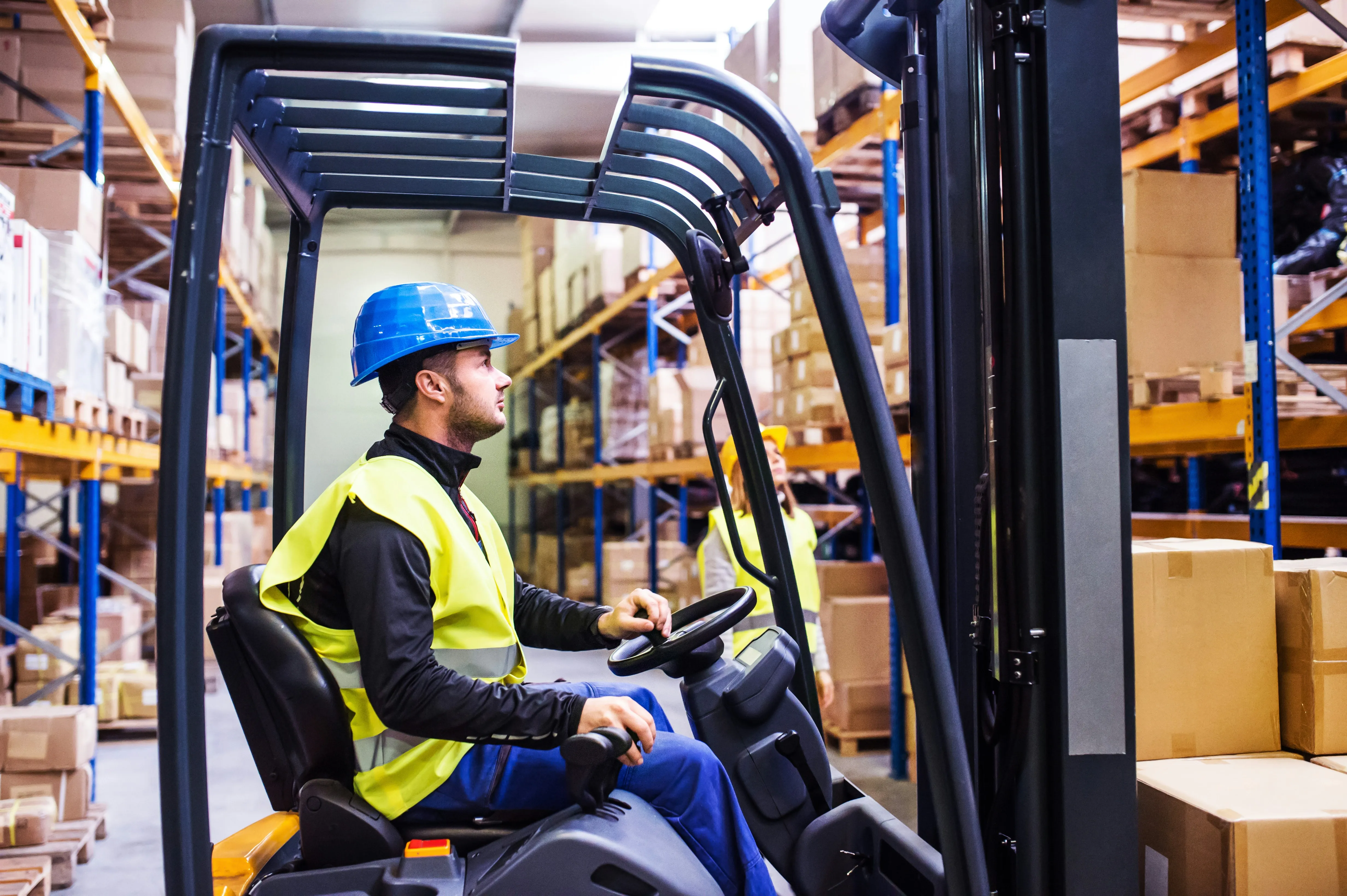 Forklift operator in warehouse with blue racking