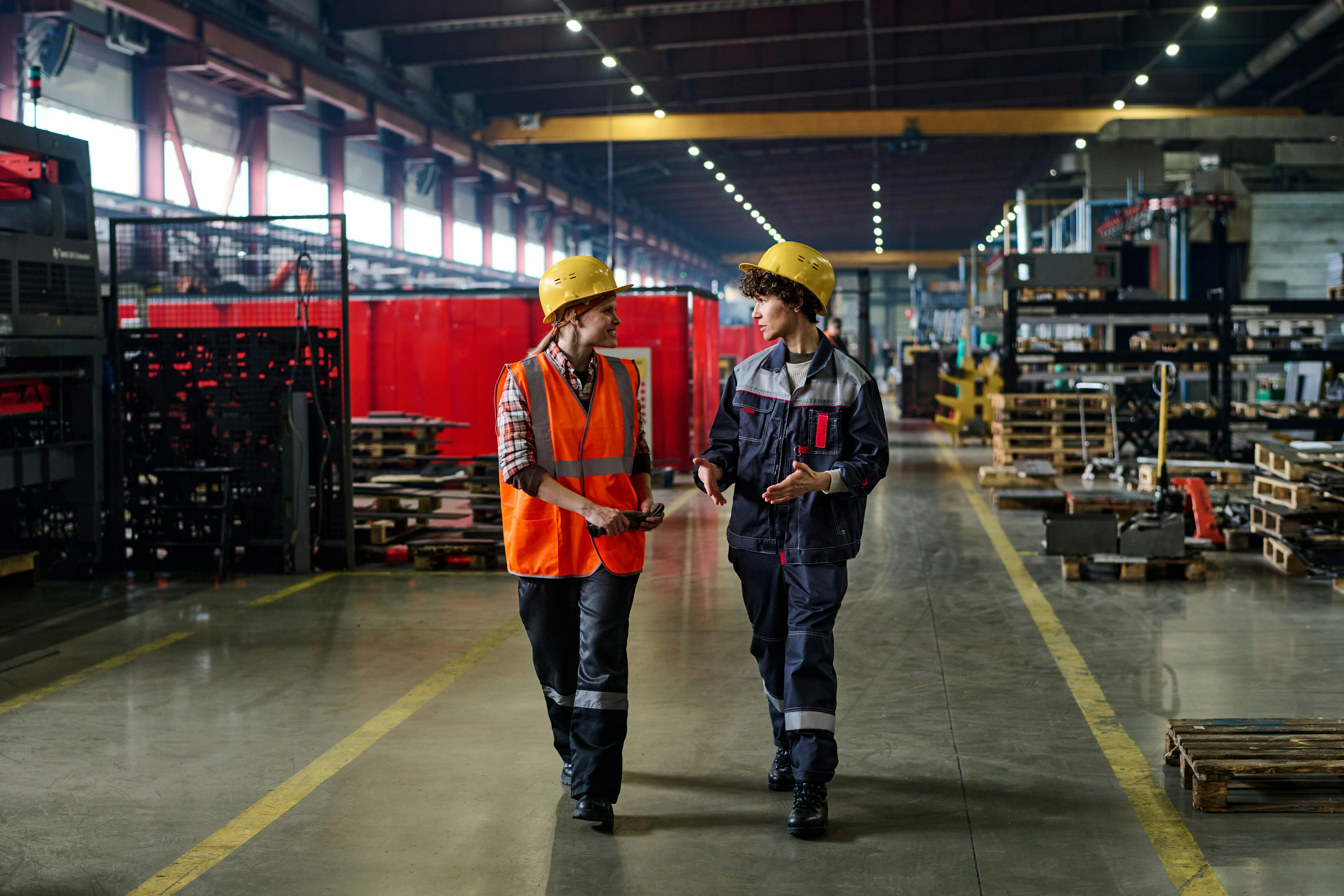 Two workers in hard hats walking through industrial manufacturing facility