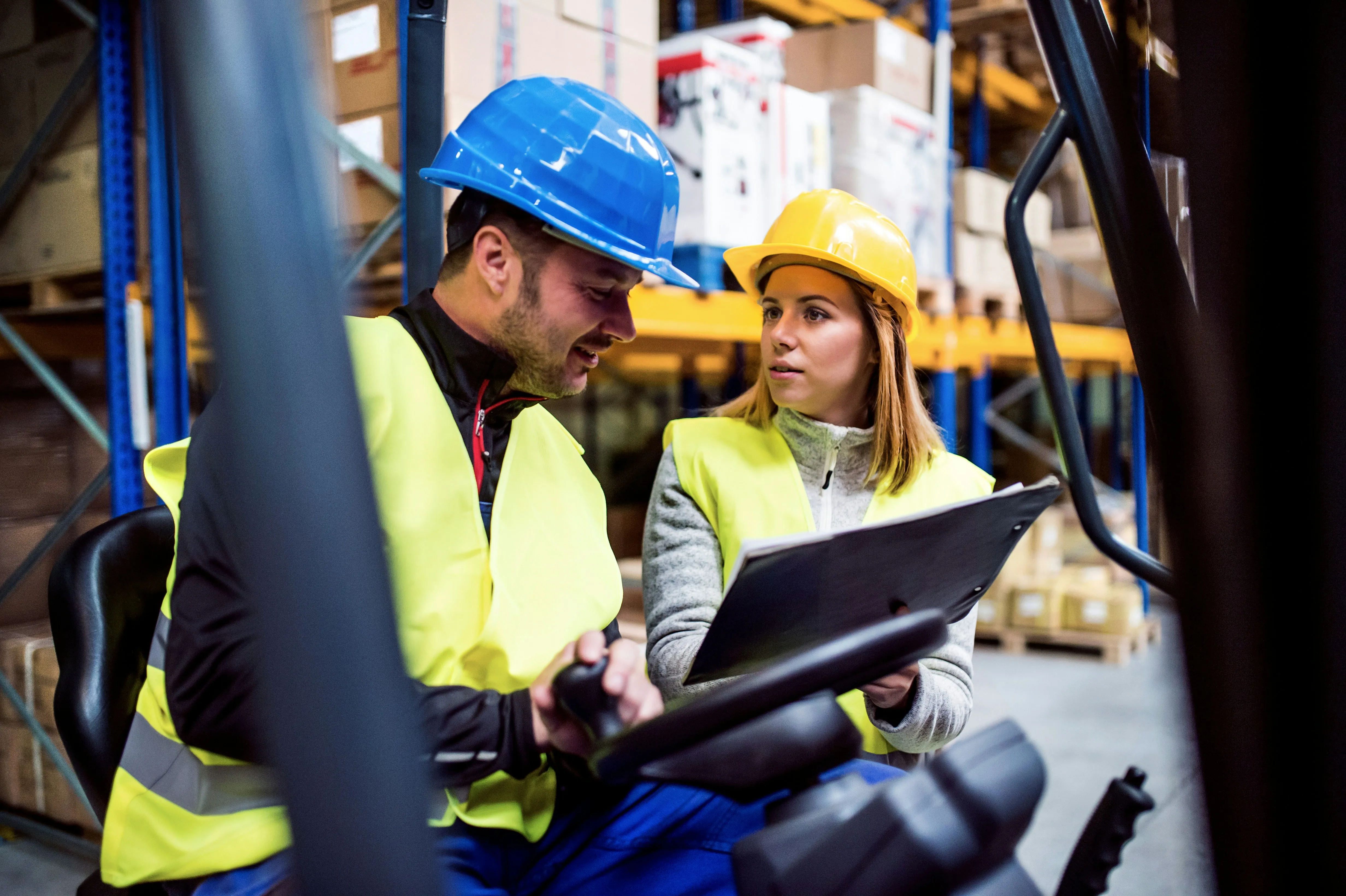 Workers reviewing clipboard together in forklift cab