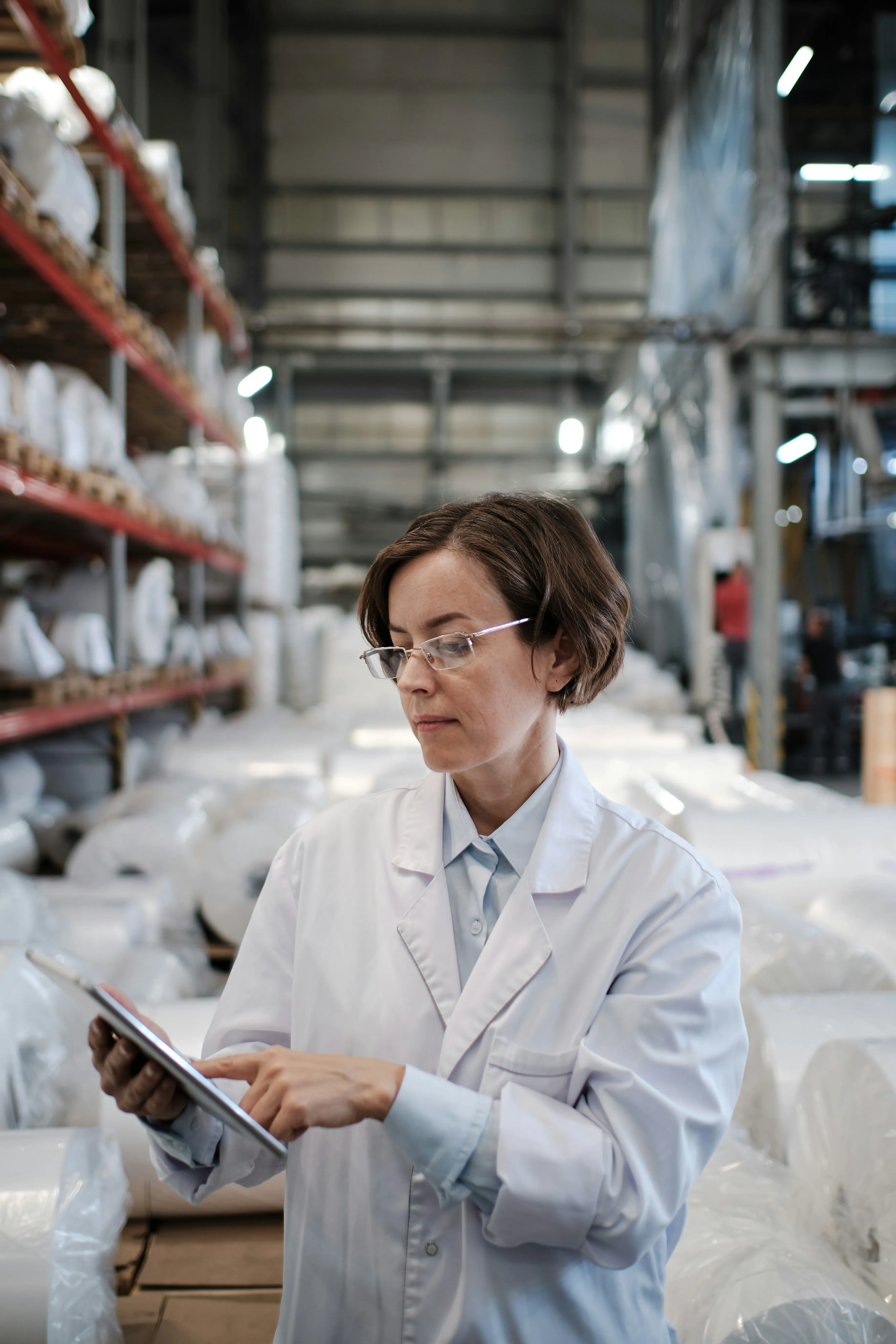 Quality inspector in lab coat using tablet in warehouse