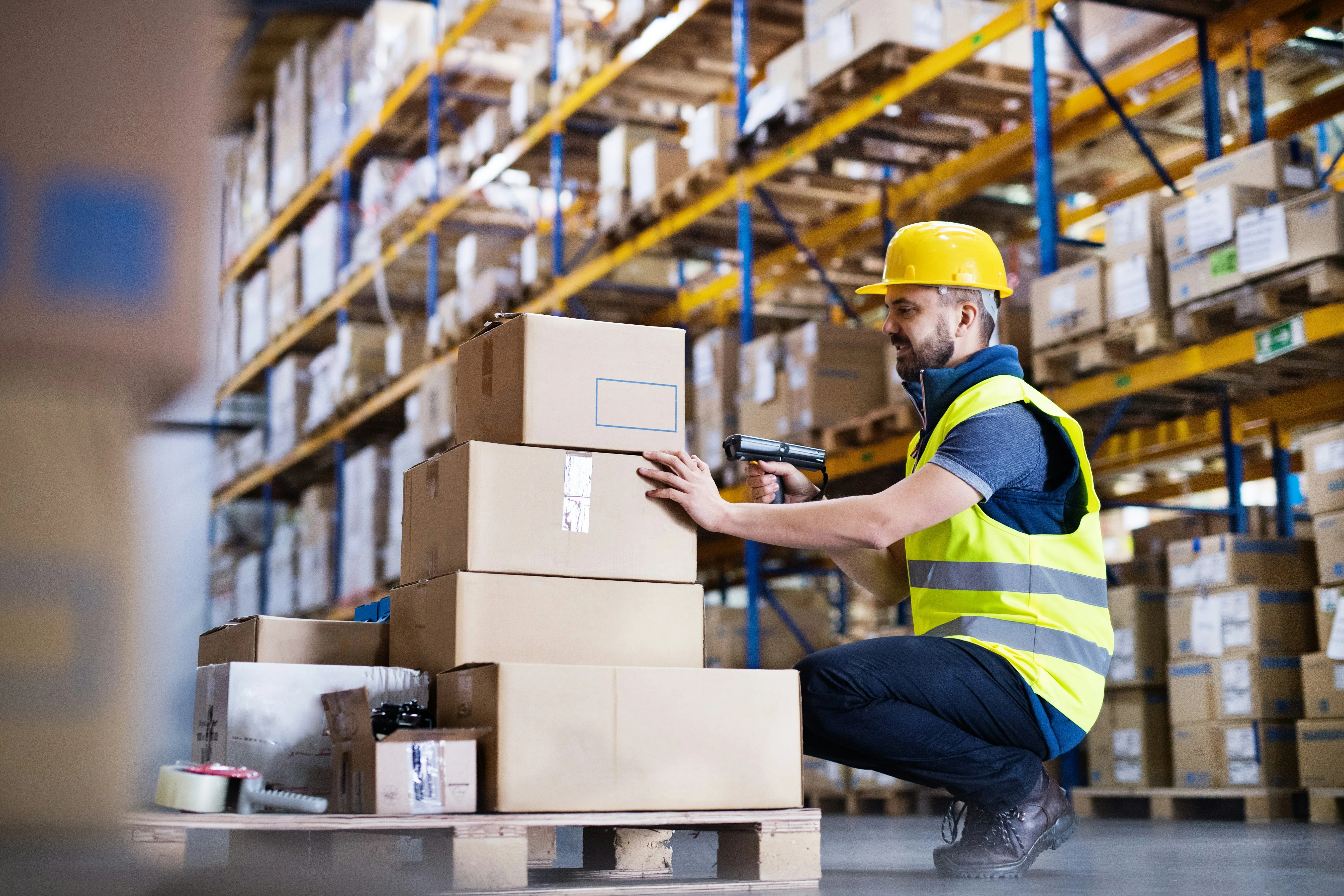 Worker scanning boxes with barcode scanner in warehouse