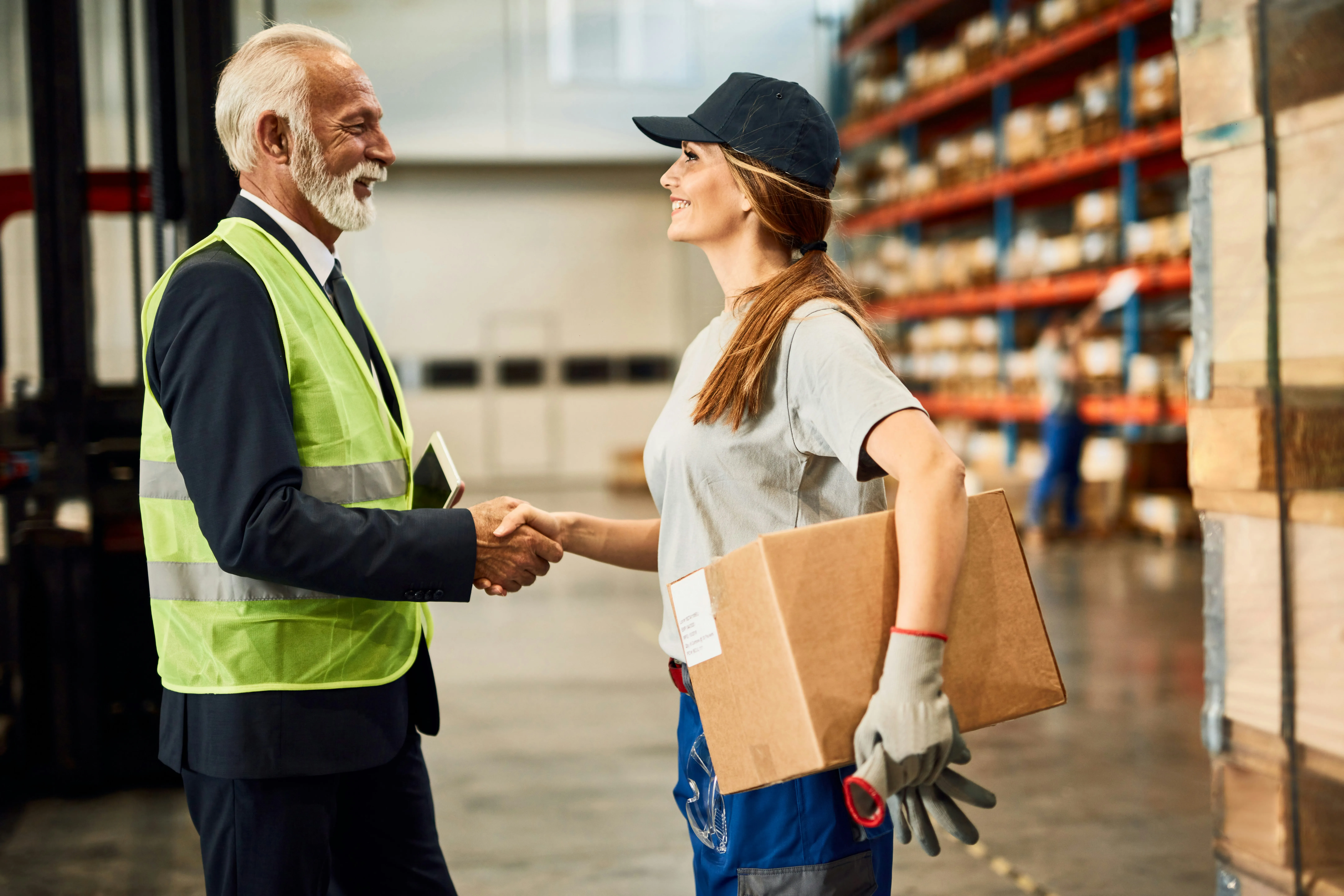 Manager shaking hands with worker in warehouse