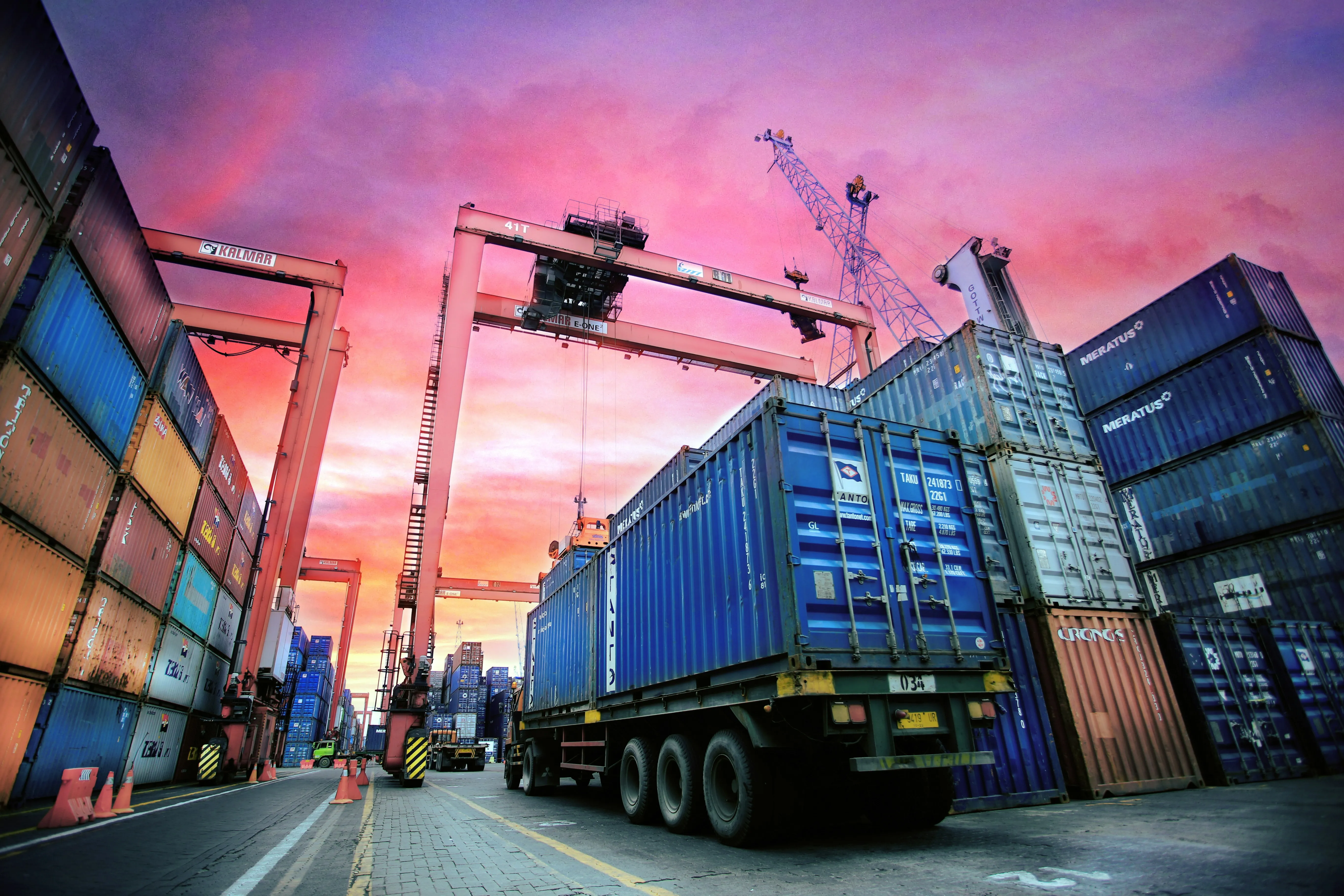 Container port at sunset with gantry cranes and trucks