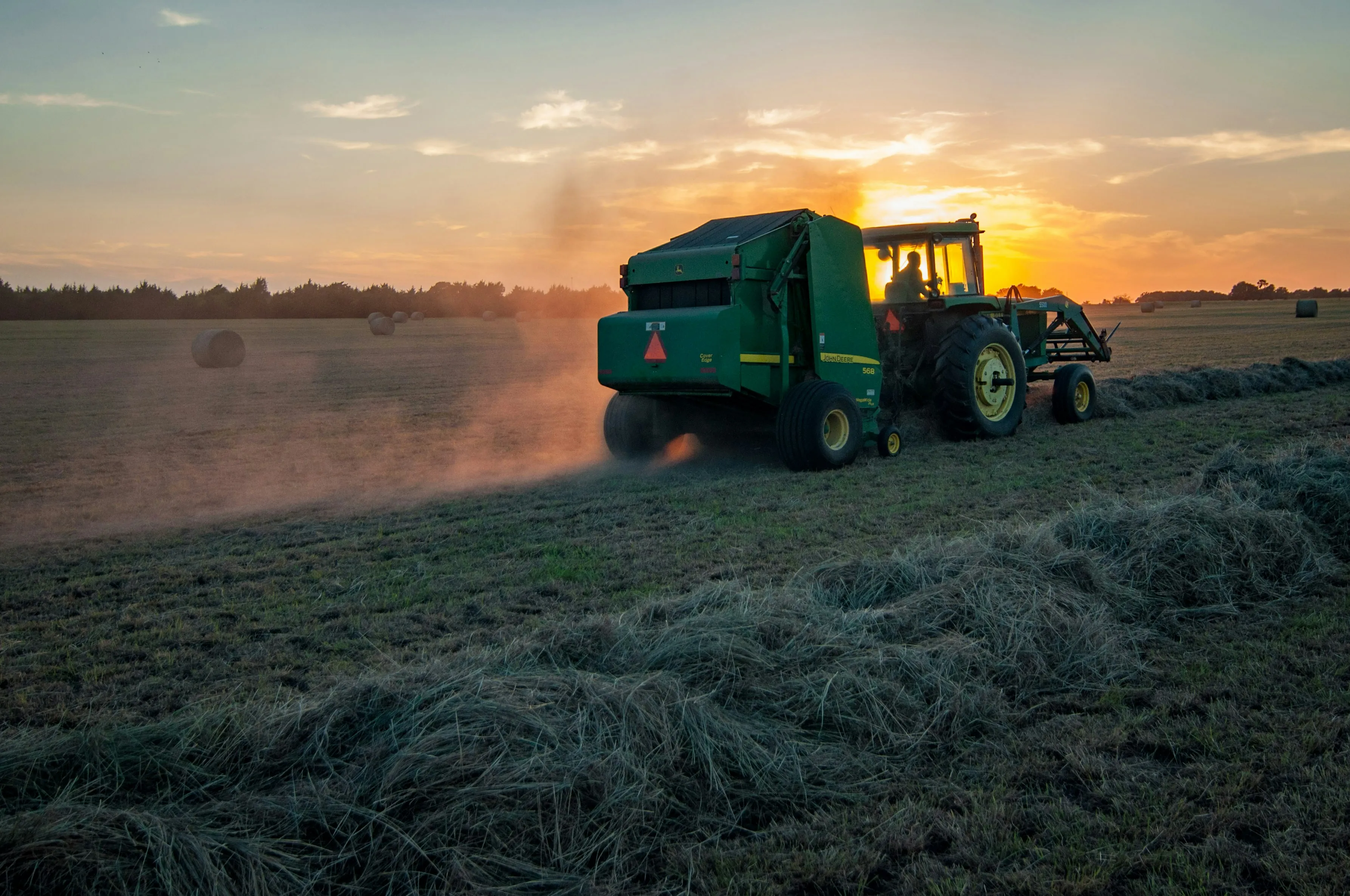 Tractor baling hay in golden sunset light