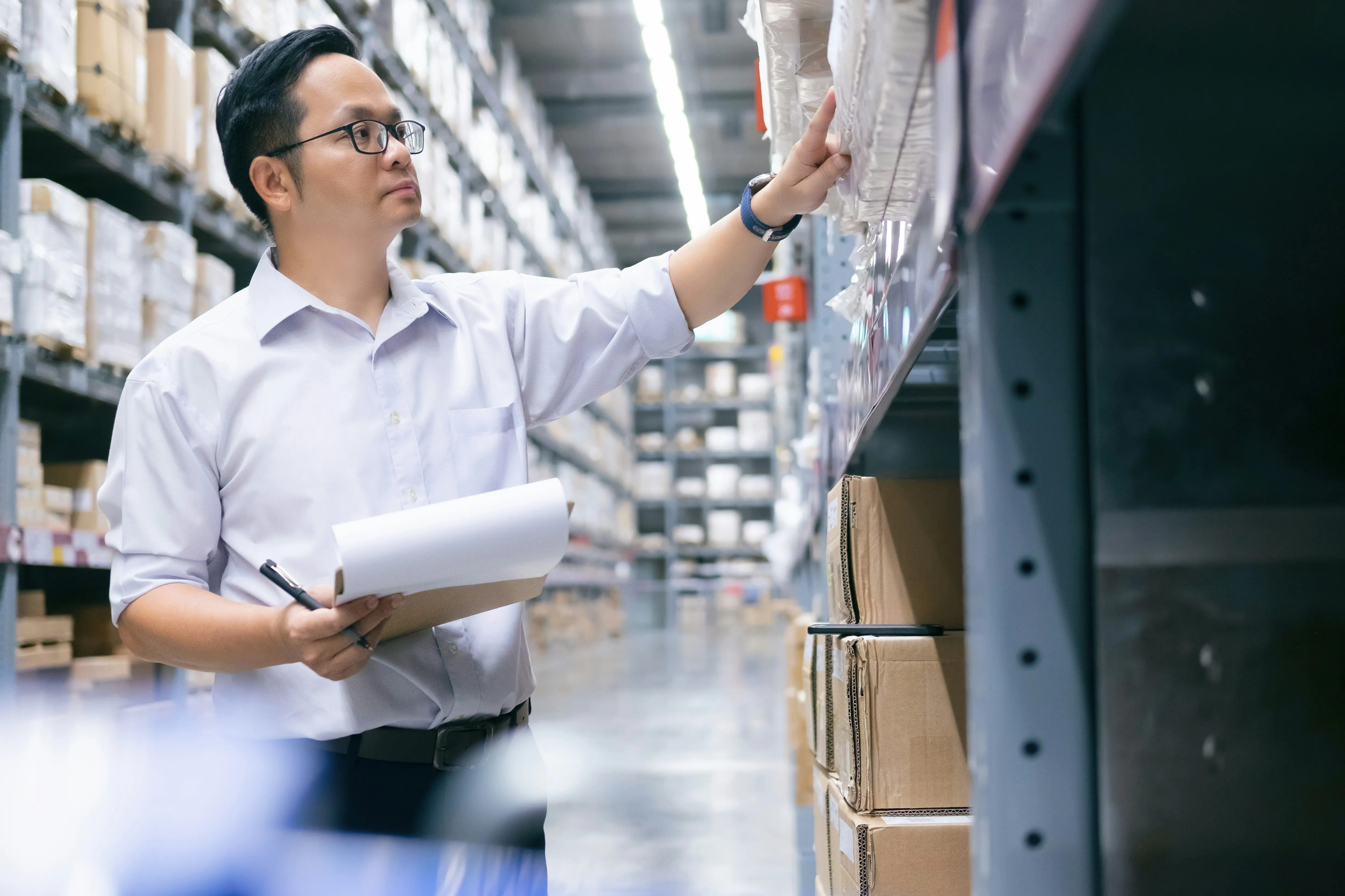 Manager checking inventory on shelves with clipboard