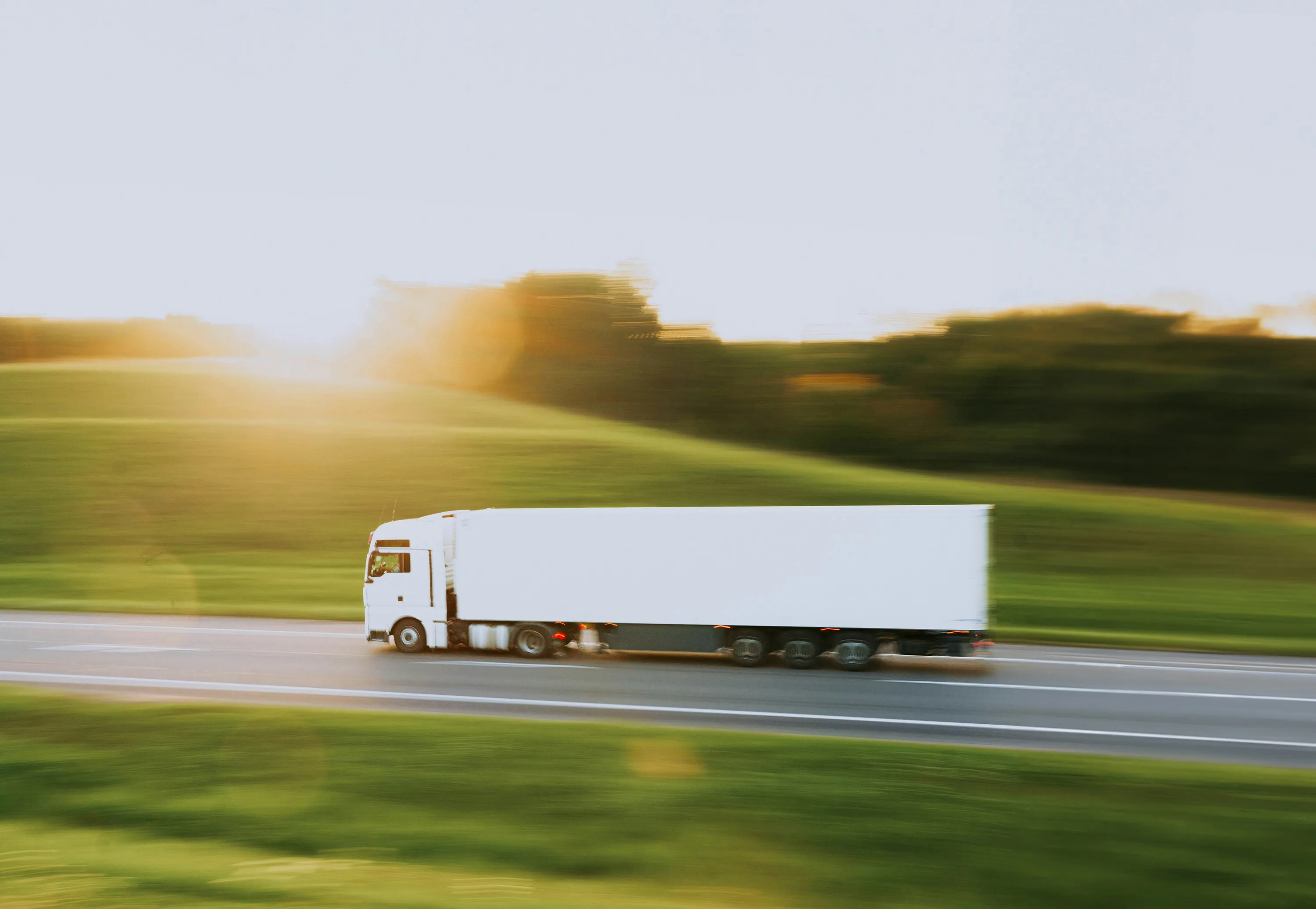 Semi-truck speeding on highway with motion blur at golden hour