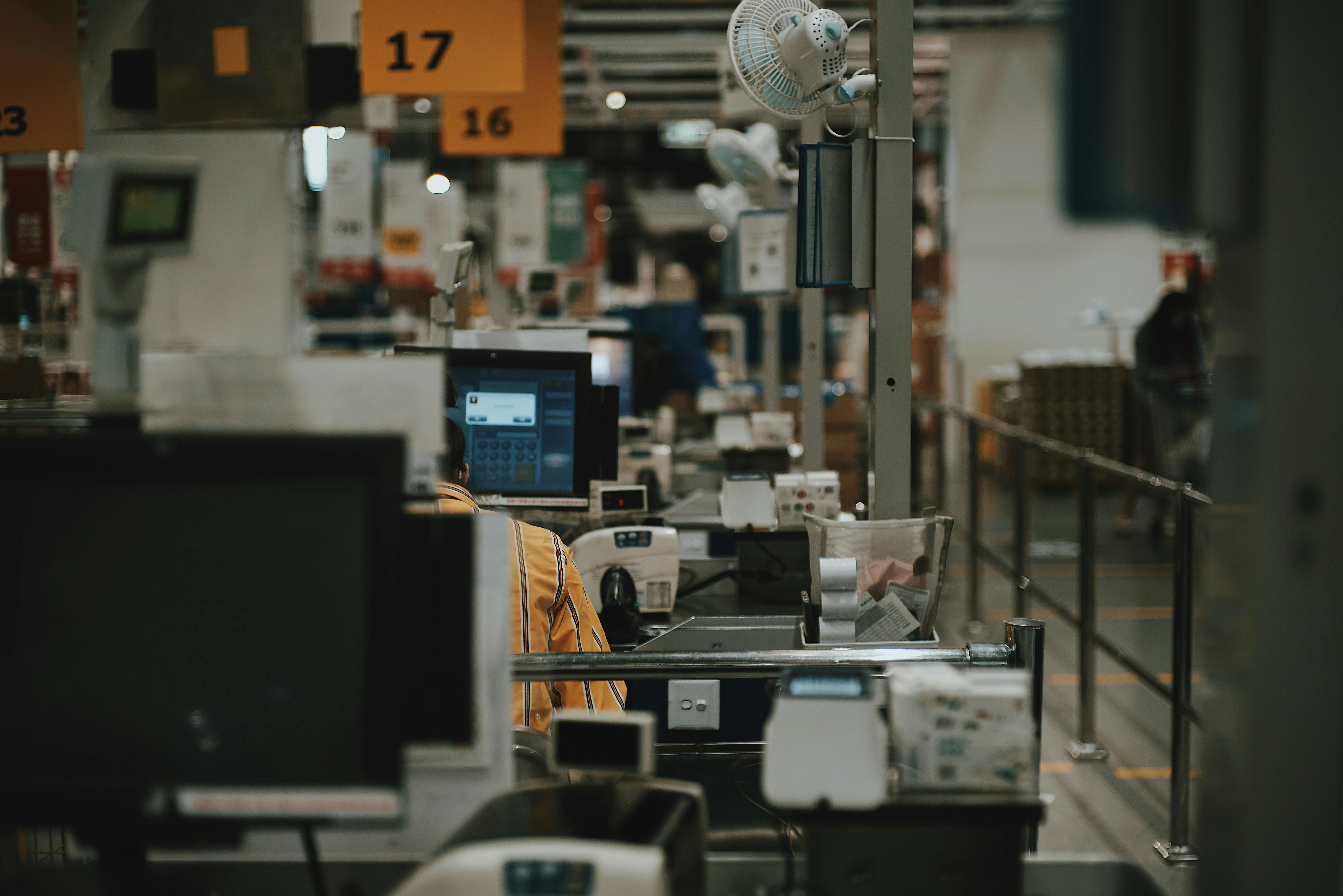 Dark cinematic factory floor with numbered aisle signs and workstations