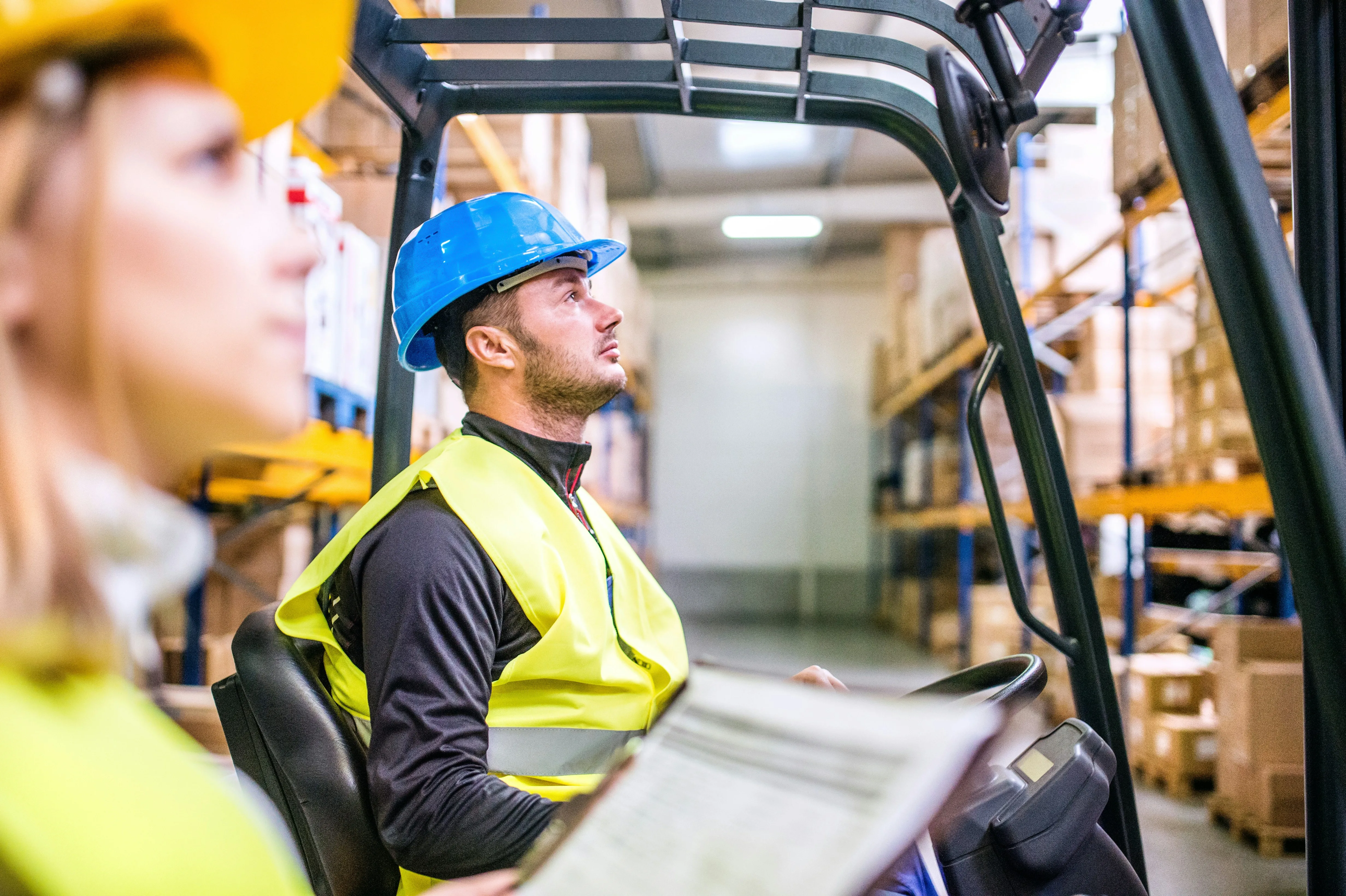 Two workers collaborating by forklift with paperwork