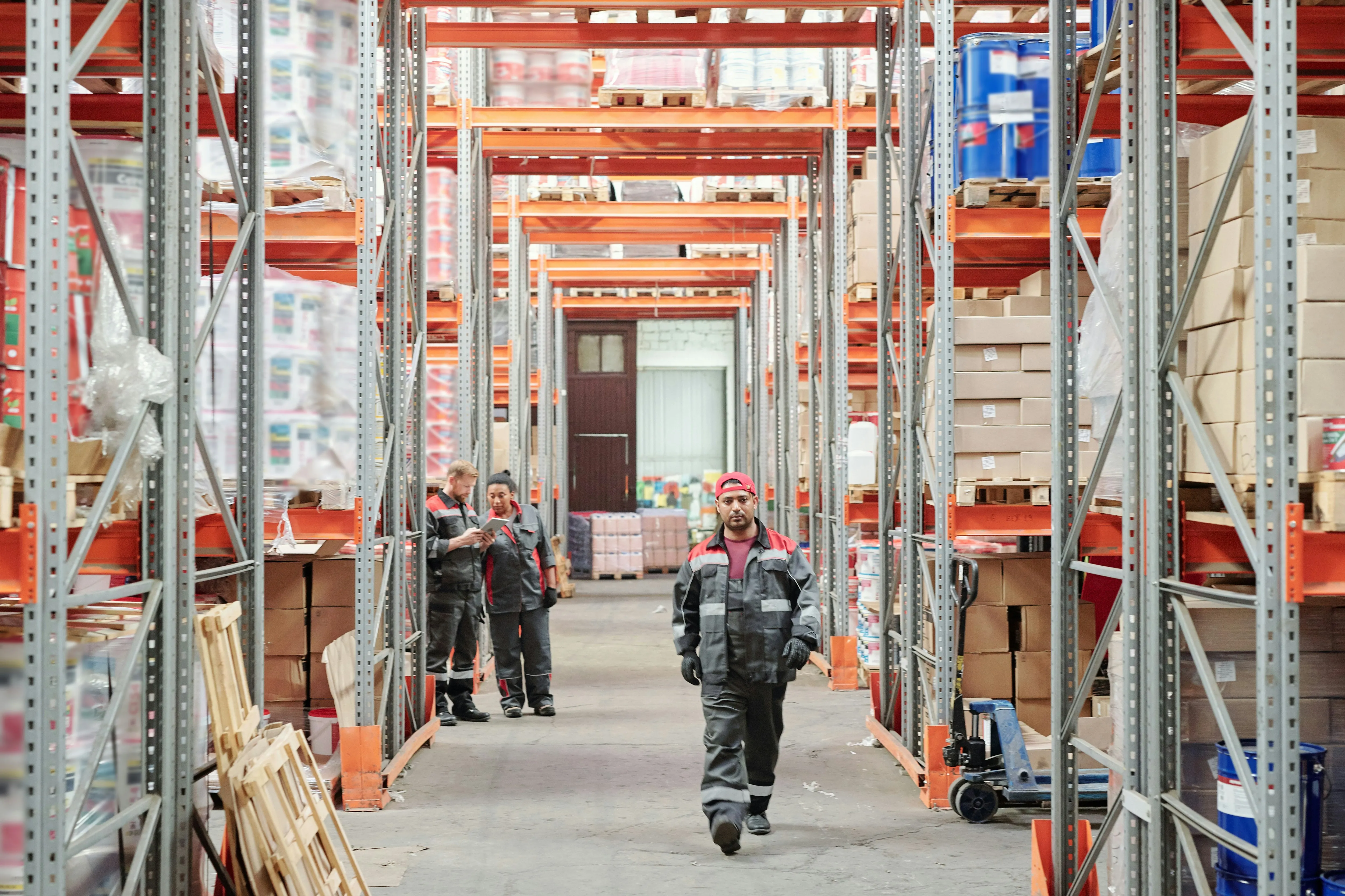 Workers walking through distribution center with orange racking