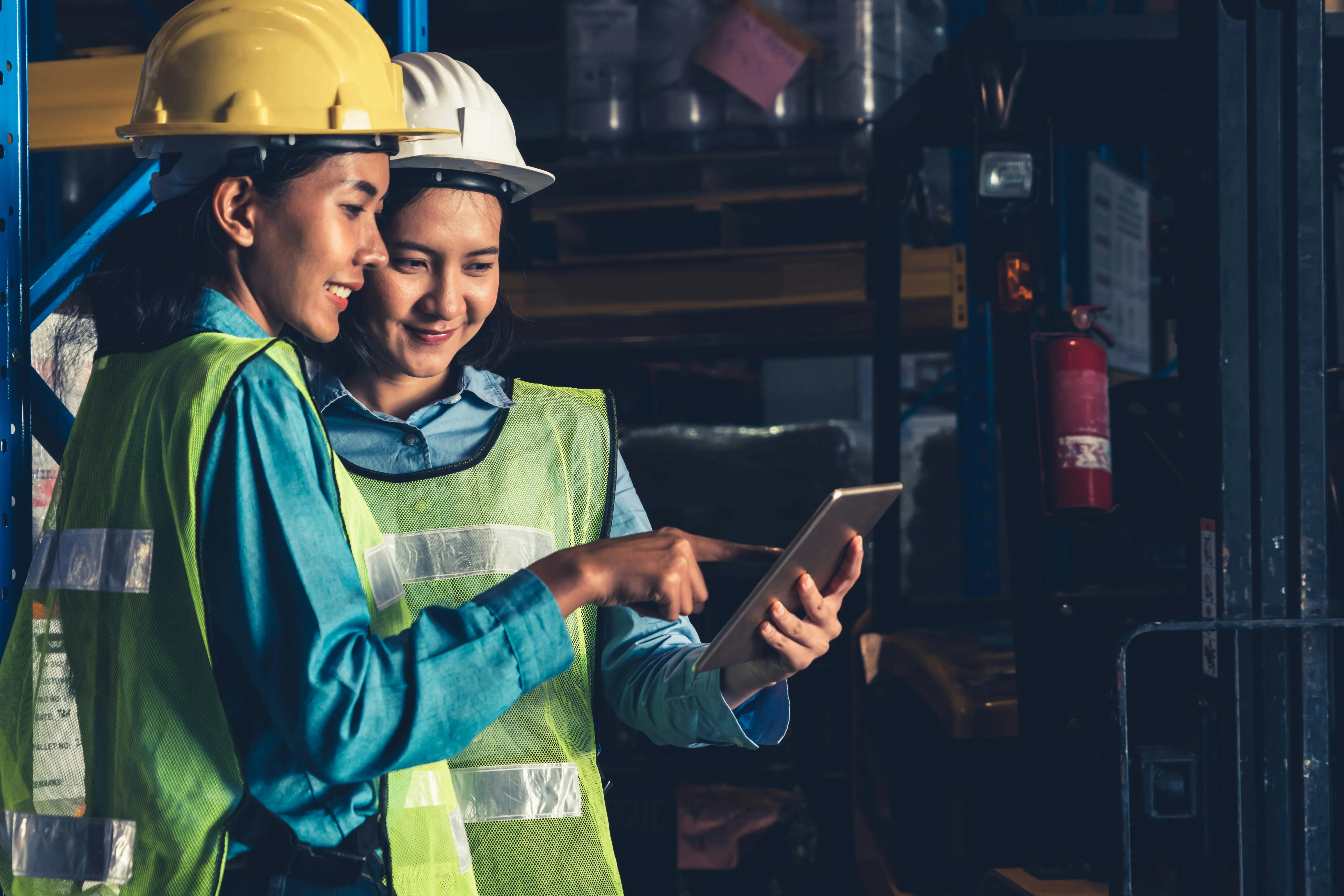 Workers reviewing data on tablet in dimly lit warehouse